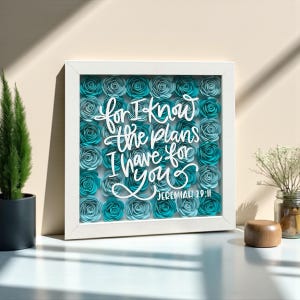 Puede incluir: Una obra de arte enmarcada con un marco blanco, llena de rosas de papel turquesa. La cita "for I know the plans I have for you" de Jeremías 29:11 está escrita en blanco, creando una pieza decorativa.