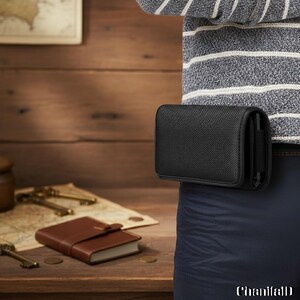 Könnte beinhalten: Eine schwarze, rechteckige, am Gürtel befestigte Handytasche. Die Tasche besteht aus einem strukturierten Material und ist an einem Gürtel befestigt. Ein braunes Leder-Notizbuch und antike Schlüssel befinden sich auf einer Holzoberfläche im Hintergrund.