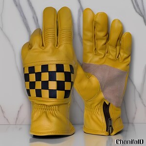 May include: A pair of yellow leather gloves with a black and yellow checkered pattern on the cuff. The gloves have a zipper closure and a tan suede patch on the palm.