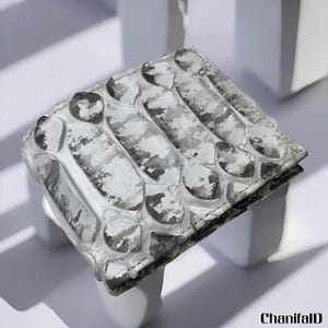 May include: A bi-fold wallet with a textured, snake-skin-like pattern in shades of white, grey, and black. The wallet is rectangular and appears to be made of leather. The brand name "ChanifalD" is visible in the bottom right corner.