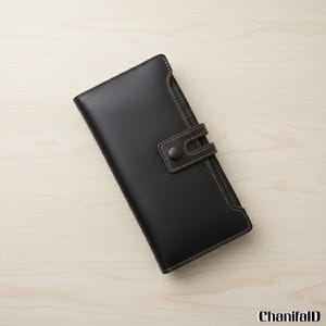 May include: A black leather wallet with a snap closure and brown stitching. The wallet has a rectangular shape and a minimalist design. The stitching is visible around the edges and on the closure strap. The wallet is closed.