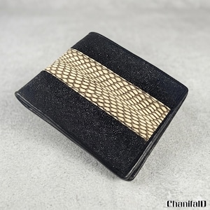 May include: A black leather wallet with a central band of beige, reptile-patterned material. The wallet is rectangular and folded. The black leather has a textured appearance. The brand name "ChanifalD" is in the bottom right corner.