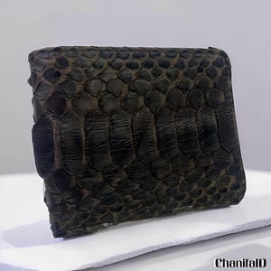 May include: A dark brown wallet with a textured, scaly pattern. The wallet appears to be made of reptile skin, possibly snake or crocodile. The wallet is rectangular and has a folded design.