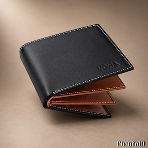 May include: A bi-fold wallet featuring a smooth black exterior with white contrast stitching and the embossed text VONA. The interior is a contrasting tan brown color, also featuring white stitching along the edges of the card slots.