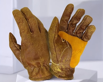 May include: A pair of brown leather work gloves with a yellow patch on the palm. The gloves have a worn, distressed appearance, suggesting durability and use. The gloves are designed for manual labor or outdoor activities.
