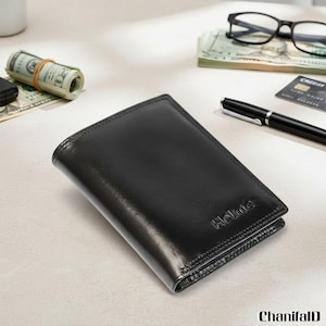 May include: A black leather wallet with the embossed brand name "Holme" is the focal point. The wallet is rectangular and appears to be new. Other items on the surface include a roll of banknotes, a pen, glasses, and a credit card.