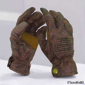 May include: A pair of brown leather gloves with a distressed finish. The gloves have a yellow patch on the palm and green button details. The gloves are designed with ribbed and padded sections.