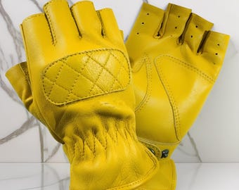 Puede incluir: Un par de guantes sin dedos de color amarillo brillante. Los guantes presentan un patrón de diamantes acolchado en el dorso de la mano y pequeños orificios de ventilación. Los guantes son de un material liso.