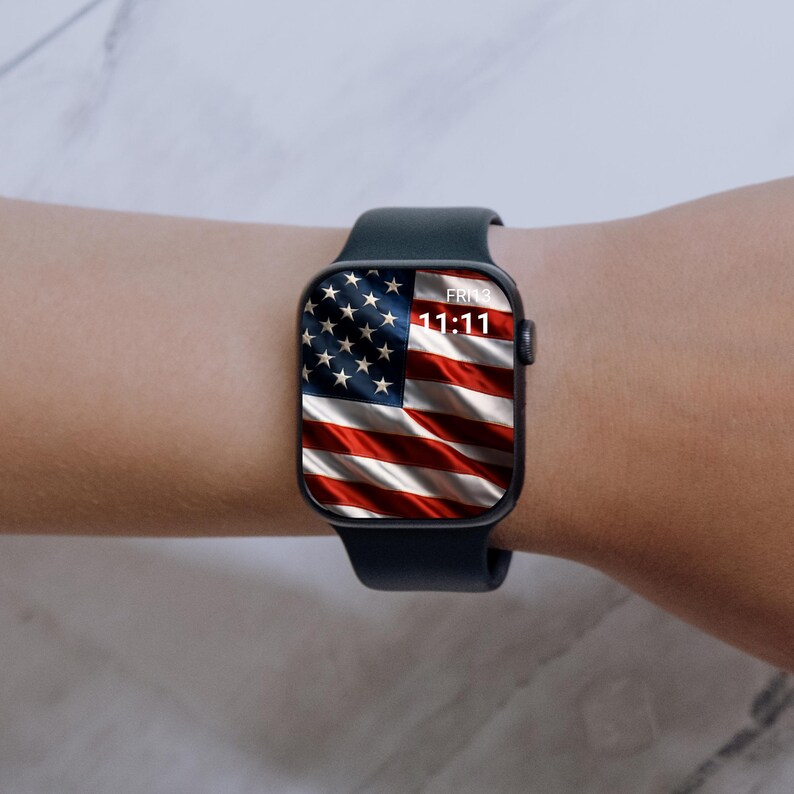 May include: A dark blue smartwatch displaying the American flag on its screen. The watch shows the time as 11:11 and the date as Fri 3. The watch is worn on a wrist.