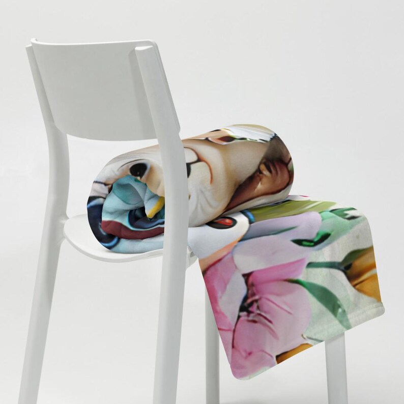 May include: A rolled-up throw blanket with a vibrant cartoon design, draped over a white chair. The blanket showcases a range of images, including a pink flower and a cartoon character. The blanket is made of soft material and is a decorative item.