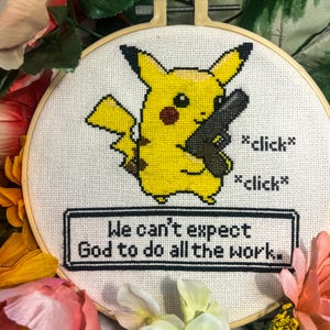 Puede incluir: Un bastidor de punto de cruz con un personaje Pikachu amarillo sosteniendo un arma negra, con el texto "*click* *click*". Debajo, el texto dice "We can't expect God to do all the work."