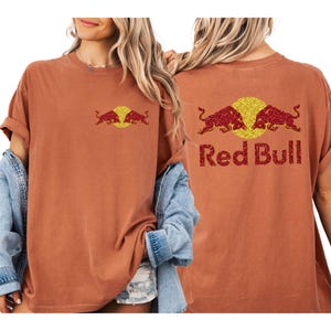 A woman wearing a red bull t-shirt with the Red Bull logo on the back.