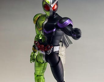 May include: A detailed action figure of a character with a split design: green and black. The figure has a helmet with a silver and green top, red eyes, and a belt. The figure is on a clear stand. Text on the base reads "ArrowModelBuild".