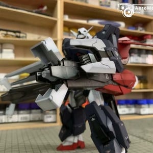 Puede incluir: Modelo detallado de un robot mecha, con una combinaci&oacute;n de colores blanco, azul marino, rojo y gris. El robot tiene extremidades articuladas y est&aacute; posado en una postura din&aacute;mica. El logotipo de AeroModelBuild es visible en la esquina superior derecha.