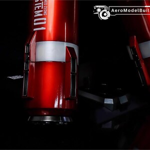 May include: Close-up of a red and white model component with the text "STEM01" visible. The component has a metallic finish and is set against a dark background. The AeroModelBuild logo is in the top right corner.