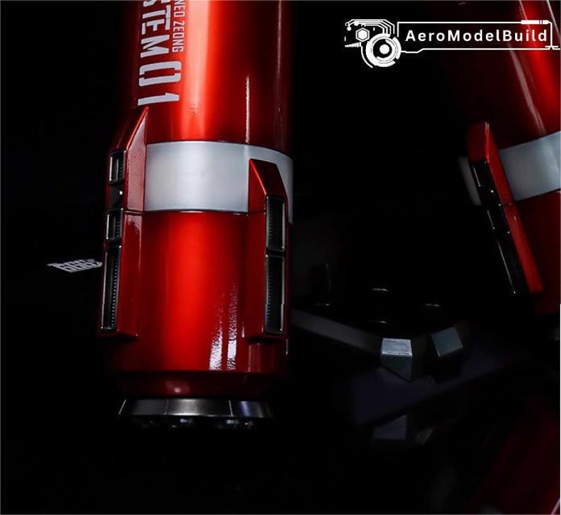 May include: Close-up of a red and white model component with the text "STEM01" visible. The component has a metallic finish and is set against a dark background. The AeroModelBuild logo is in the top right corner.