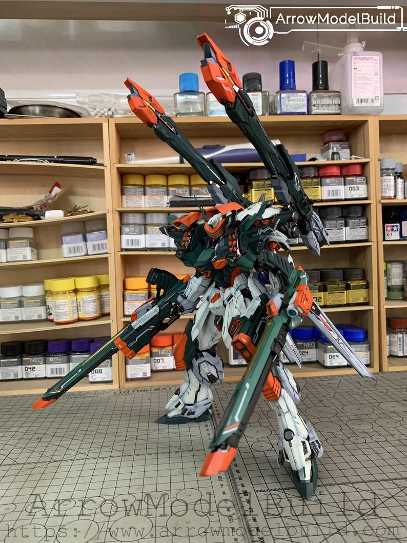 May include: A detailed model of a mech warrior, featuring a color scheme of white, green, and orange. The model has multiple weapons and is posed on a cutting mat. The text "ArrowModelBuild" is visible.
