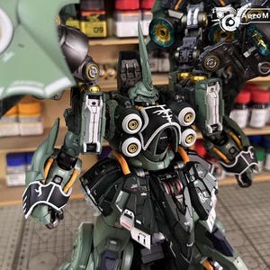 May include: A detailed model of a green and black mecha robot with intricate mechanical details. The model features multiple articulated joints, circular accents, and a prominent horn-like structure on its head. The AeroModelBuild logo is visible in the background.