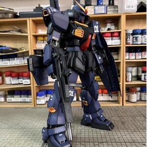 Pu&ograve; includere: Un modello dettagliato di un robot meccanico blu scuro e nero con accenti arancioni e rossi. Il robot tiene in mano una grossa pistola e ha il numero "01" stampato sulla gamba e sul petto. Il testo "AeroModelBuild" &egrave; visibile in alto a destra.