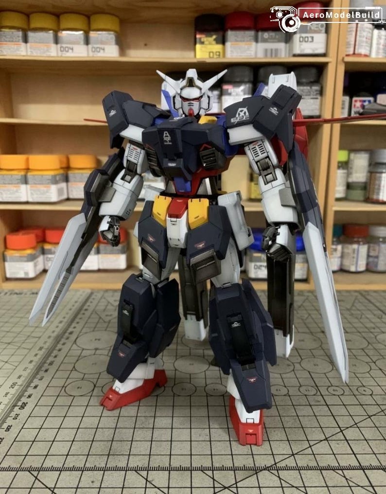 Puede incluir: Modelo detallado de un robot mecha, con una combinaci&oacute;n de colores azul marino, blanco, rojo y amarillo. El robot tiene extremidades grandes y articuladas y est&aacute; equipado con dos grandes cuchillas plateadas. El modelo est&aacute; sobre una superficie cuadriculada.