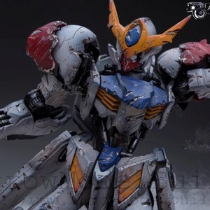 May include: Detailed model of a battle-worn robot with a white, blue, orange, and red color scheme. The robot has intricate mechanical details, visible damage, and a dynamic pose. The image includes the text "ArrowModelBuild".