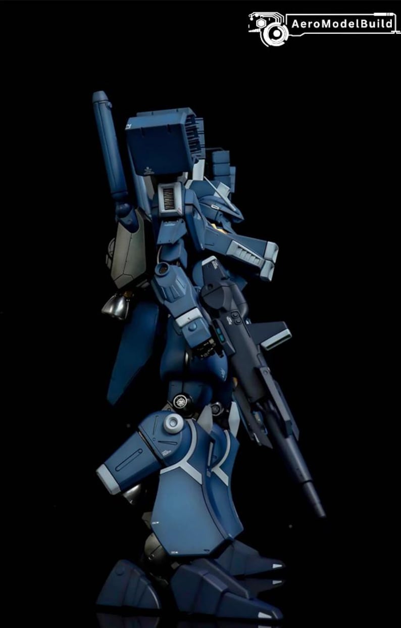 May include: A detailed side view of a dark blue model robot with a gun. The robot has multiple panels, joints, and a large backpack. The AeroModelBuild logo is in the top right corner.