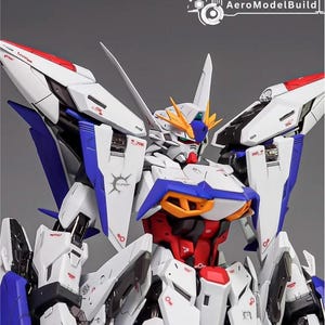 Puede incluir: Modelo detallado de un robot mecha blanco, azul, rojo y amarillo. El robot tiene paneles y elementos de dise&ntilde;o intrincados, con el texto "AeroModelBuild" visible. La cabeza del robot presenta una cresta distintiva y m&uacute;ltiples antenas.