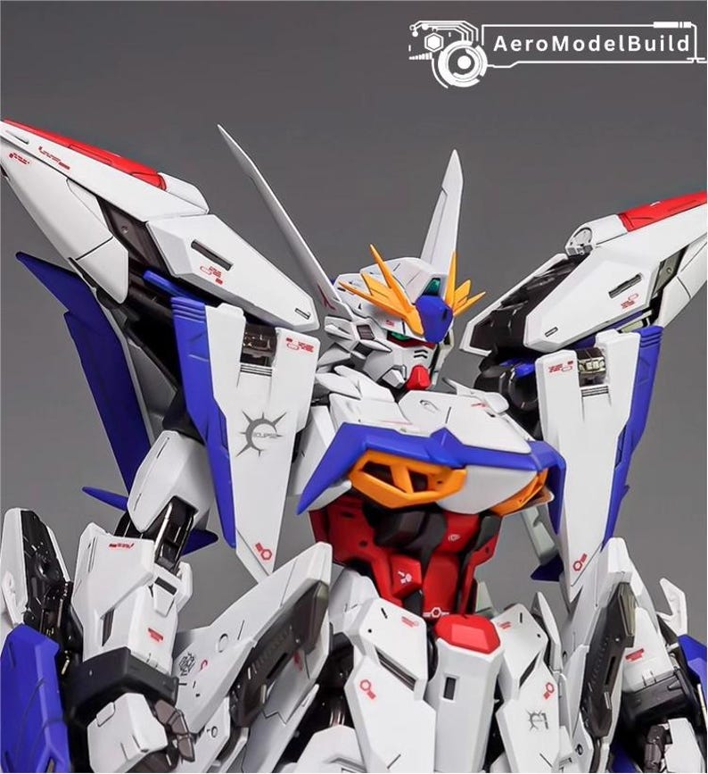 Puede incluir: Modelo detallado de un robot mecha blanco, azul, rojo y amarillo. El robot tiene paneles y elementos de dise&ntilde;o intrincados, con el texto "AeroModelBuild" visible. La cabeza del robot presenta una cresta distintiva y m&uacute;ltiples antenas.