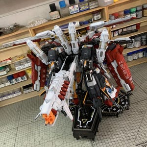 Puede incluir: Un kit de modelo detallado de un robot mec&aacute;nico, con un dise&ntilde;o complejo con acentos rojos, blancos, negros y naranjas. El modelo tiene m&uacute;ltiples partes articuladas y se muestra en un soporte negro. El texto "ArrowModelBuild" es visible.