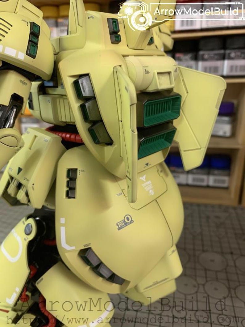 May include: A detailed, assembled model kit of a yellow and green mech robot. The model features intricate panel lines, vents, and markings. The robot has a rounded body with angular armor plates and a complex design.