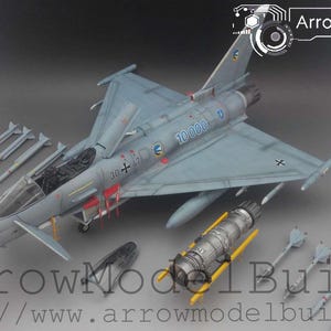 May include: A detailed model of a light blue military jet fighter with multiple missiles and a separate engine component. The model has the number "10000" on the side and the text "ArrowModelBuild".