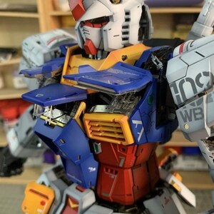 K&ouml;nnte beinhalten: Detailliertes Modell eines Gundam-Roboters mit einem wei&szlig;en Kopf mit roten und gelben Akzenten. Der Roboter-K&ouml;rper besteht aus blauen, roten, gelben und grauen Paneelen mit komplizierten mechanischen Details. Der Text "AeroModelBuild" ist enthalten.