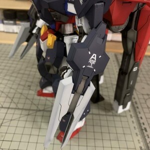 Puede incluir: Modelo detallado de un robot con esquema de color azul oscuro y rojo. El robot tiene un escudo grande con la letra "A" y el texto "AGE 1" impreso. El modelo est&aacute; sobre una superficie cuadriculada.