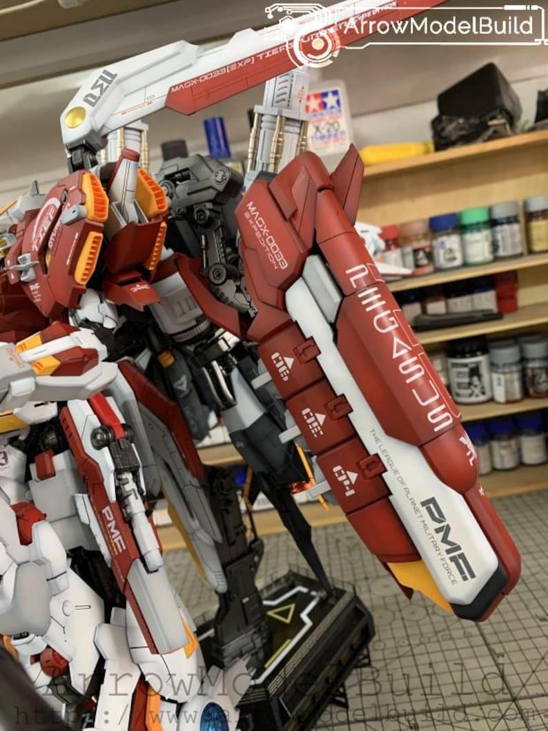 Puede incluir: Modelo detallado de un robot con armadura roja, blanca y gris. El modelo tiene m&uacute;ltiples partes articuladas y est&aacute; etiquetado con texto que incluye "MAGX-0033" y "PME". El modelo est&aacute; sobre un soporte negro, con un acento amarillo y blanco.