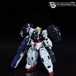 May include: A white and blue model robot with red and yellow accents. The robot has large shoulder armor and a detailed design. The image is set against a dark background.