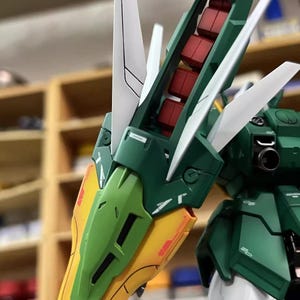 May include: Detailed view of a green, white, yellow, and red model kit. The model displays complex mechanical parts, with angular panels and articulated sections. The text "ArrowModelBuild" and a website address are visible.