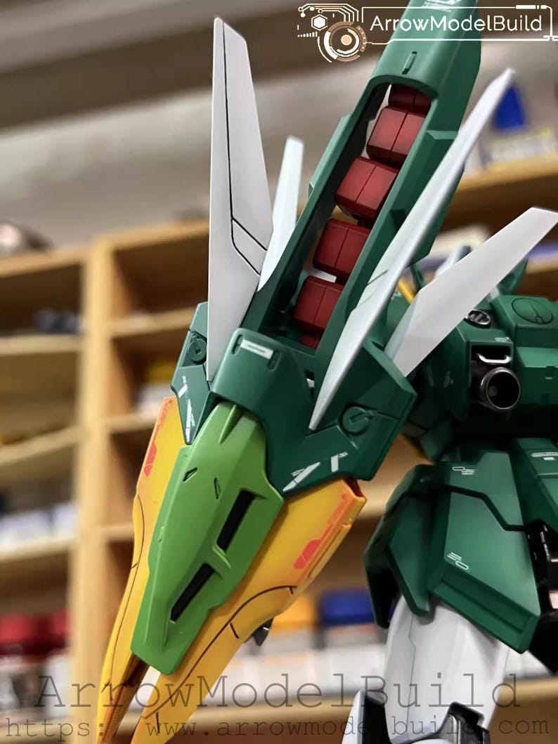 May include: Detailed view of a green, white, yellow, and red model kit. The model displays complex mechanical parts, with angular panels and articulated sections. The text "ArrowModelBuild" and a website address are visible.