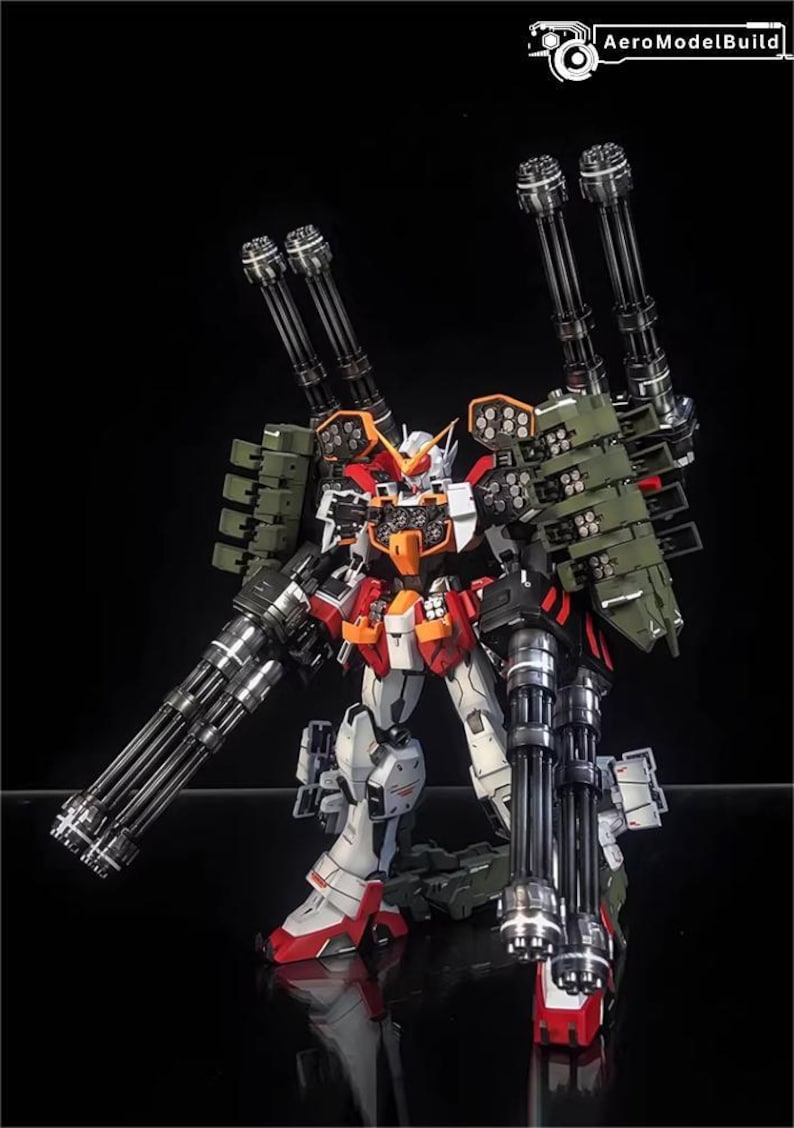 May include: A detailed model of a Gundam robot, with a colour scheme of white, red, orange, and green. The robot is heavily armed with multiple large cannons and missile launchers, showcasing a complex design. The AeroModelBuild logo is visible.