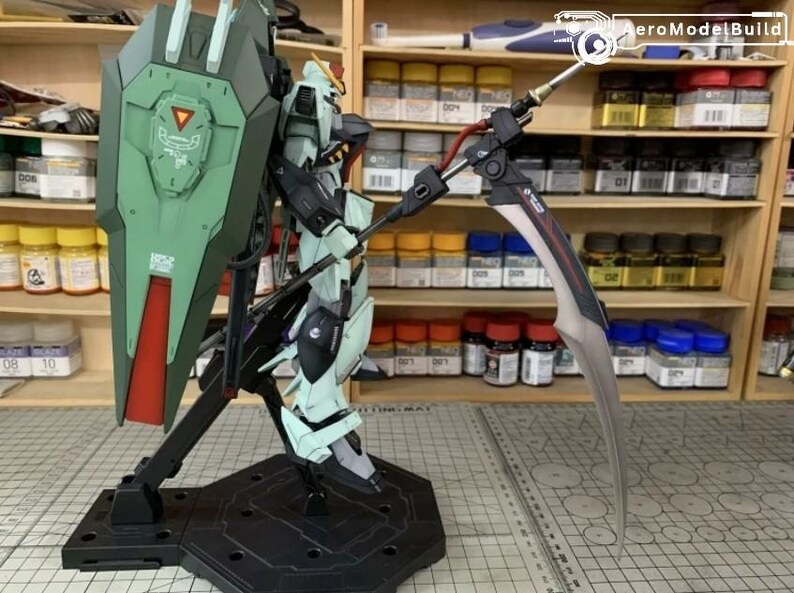 Puede incluir: Maqueta detallada de un robot Gundam, con una combinaci&oacute;n de colores verde y blanco, un gran escudo y una larga hoja curva. El modelo est&aacute; montado sobre un soporte negro, mostrando intrincados detalles mec&aacute;nicos.