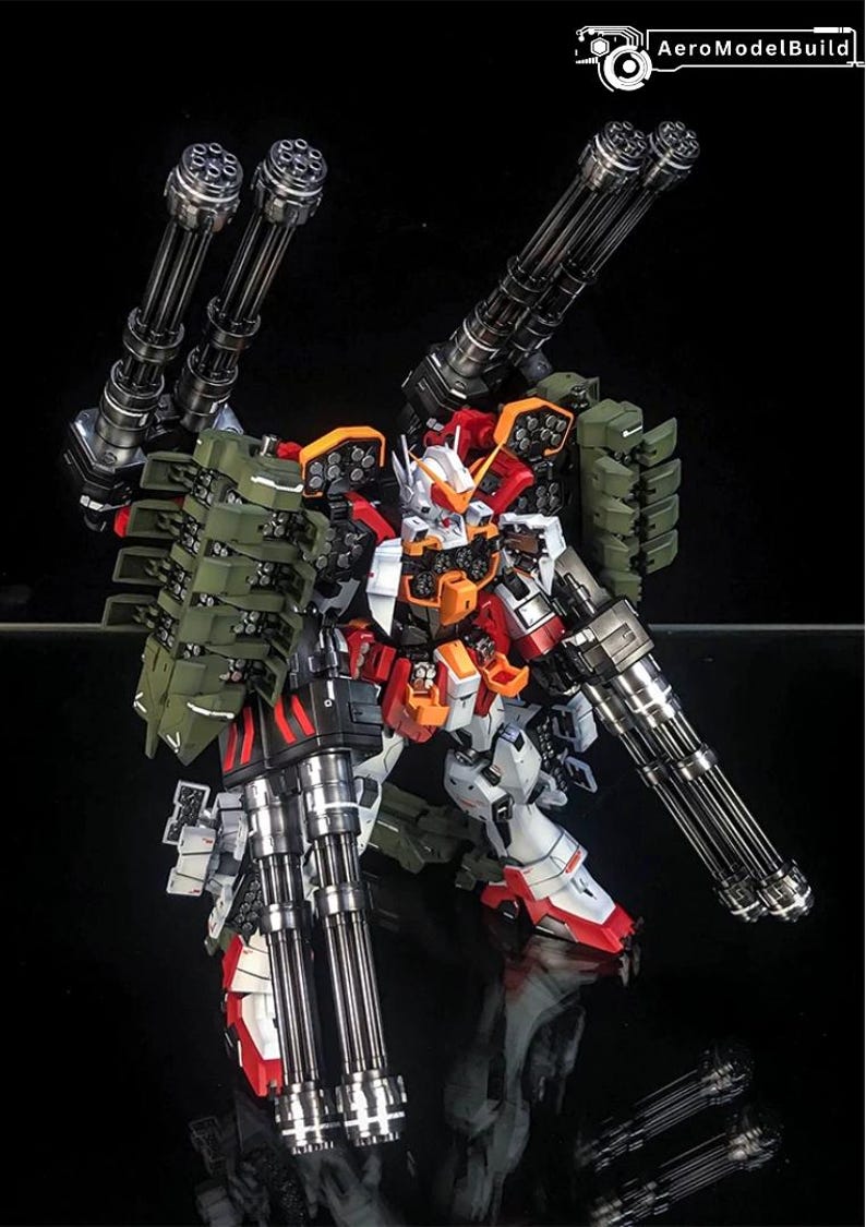K&ouml;nnte beinhalten: Ein wei&szlig;er, roter und orangefarbener Robotermodellbausatz mit vier gro&szlig;en metallischen Gatling-Kanonen an Schultern und Armen sowie olivgr&uuml;nen Raketenwerfern auf dem R&uuml;cken. Die Figur zeigt detaillierte mechanische Elemente und den Schriftzug AeroModelBuild.