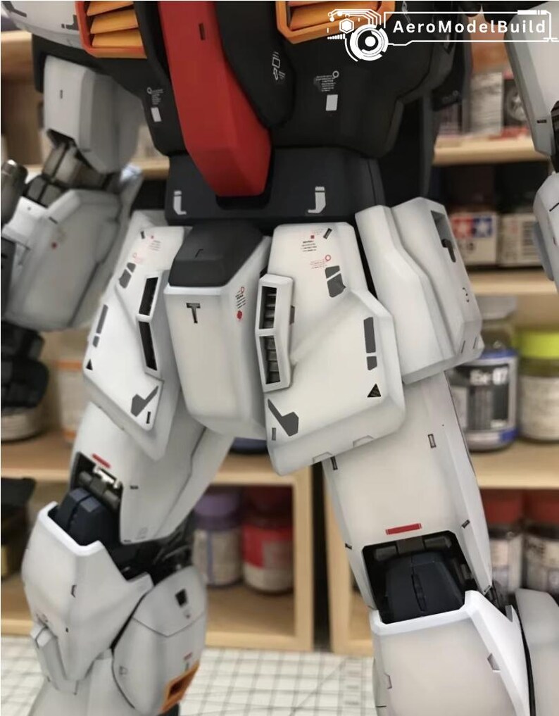 Op de afbeelding: Close-up van een gedetailleerde witte en zwarte modelrobot, met rode en oranje accenten. Het model heeft ingewikkelde paneellijnen en markeringen, wat wijst op een hoog niveau van vakmanschap. De afbeelding benadrukt de texturen en details van het model.