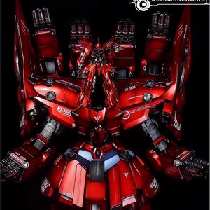 May include: A detailed, red model robot with multiple weapons and intricate mechanical details. The model features the text "NZ-995" and "NEO ZEONG". The robot is set against a black background, highlighting its metallic finish.