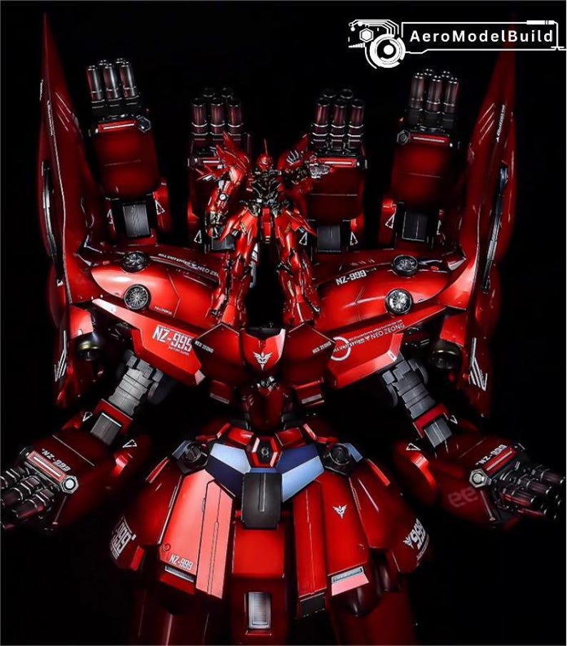 May include: A detailed, red model robot with multiple weapons and intricate mechanical details. The model features the text "NZ-995" and "NEO ZEONG". The robot is set against a black background, highlighting its metallic finish.