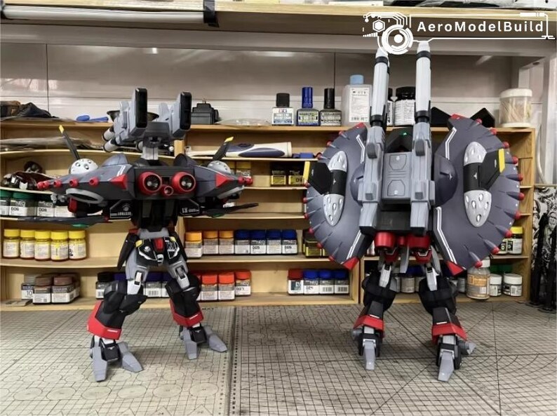 May include: Two detailed model robots, one facing forward and the other backward, with a workshop background. The robots are primarily black, red, and gray, with intricate designs and mechanical features. The AeroModelBuild logo is visible.