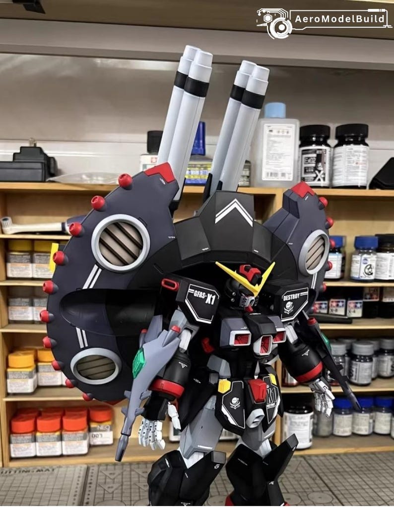 May include: A detailed model of a black, red, and gray mecha robot with large shoulder-mounted cannons. The robot has intricate detailing, including vents, panels, and the text "GFAS-X1" and "DESTROY". The model is set against a backdrop of shelves with various containers.