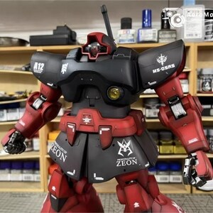May include: A detailed model of a red and black robot with the text "A12" and "MS-0SRS" visible. The robot has a detailed design with multiple panels and joints. The model is set against a background of shelves filled with various bottles and containers.