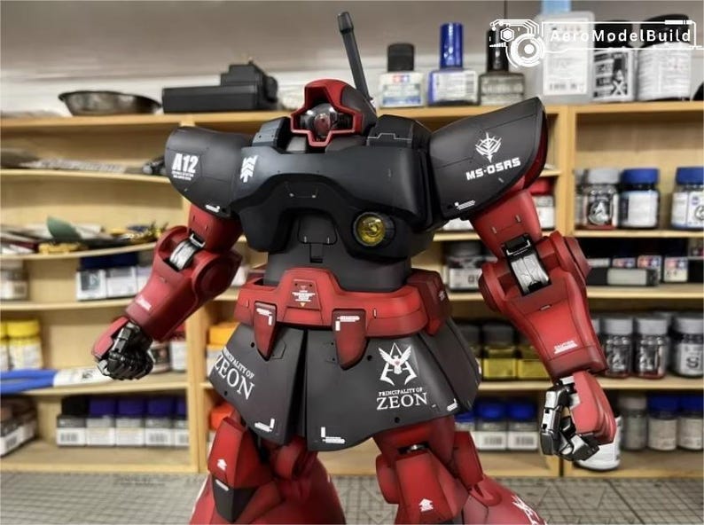 May include: A detailed model of a red and black robot with the text "A12" and "MS-0SRS" visible. The robot has a detailed design with multiple panels and joints. The model is set against a background of shelves filled with various bottles and containers.