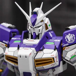 May include: A detailed model of a Gundam robot, featuring a color scheme of white, purple, and gold accents. The robot has a complex design with sharp angles and intricate paneling. The head has two prominent white antennae. The AeroModelBuild logo is in the top right corner.