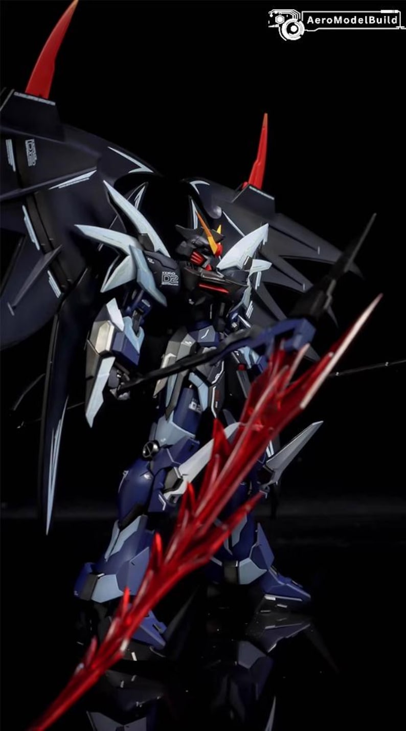 Puede incluir: Un modelo detallado de un robot futurista, principalmente en tonos de azul, negro y blanco, con detalles en rojo. El robot sostiene una gran espada roja y tiene alas. El logotipo de AeroModelBuild est&aacute; en la esquina superior derecha.