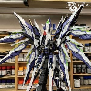 May include: A detailed model kit of a mech with large, stylized wings. The model features a colour scheme of white, purple, and green accents. The image includes the text "AutoModelBuild" in the upper right corner.